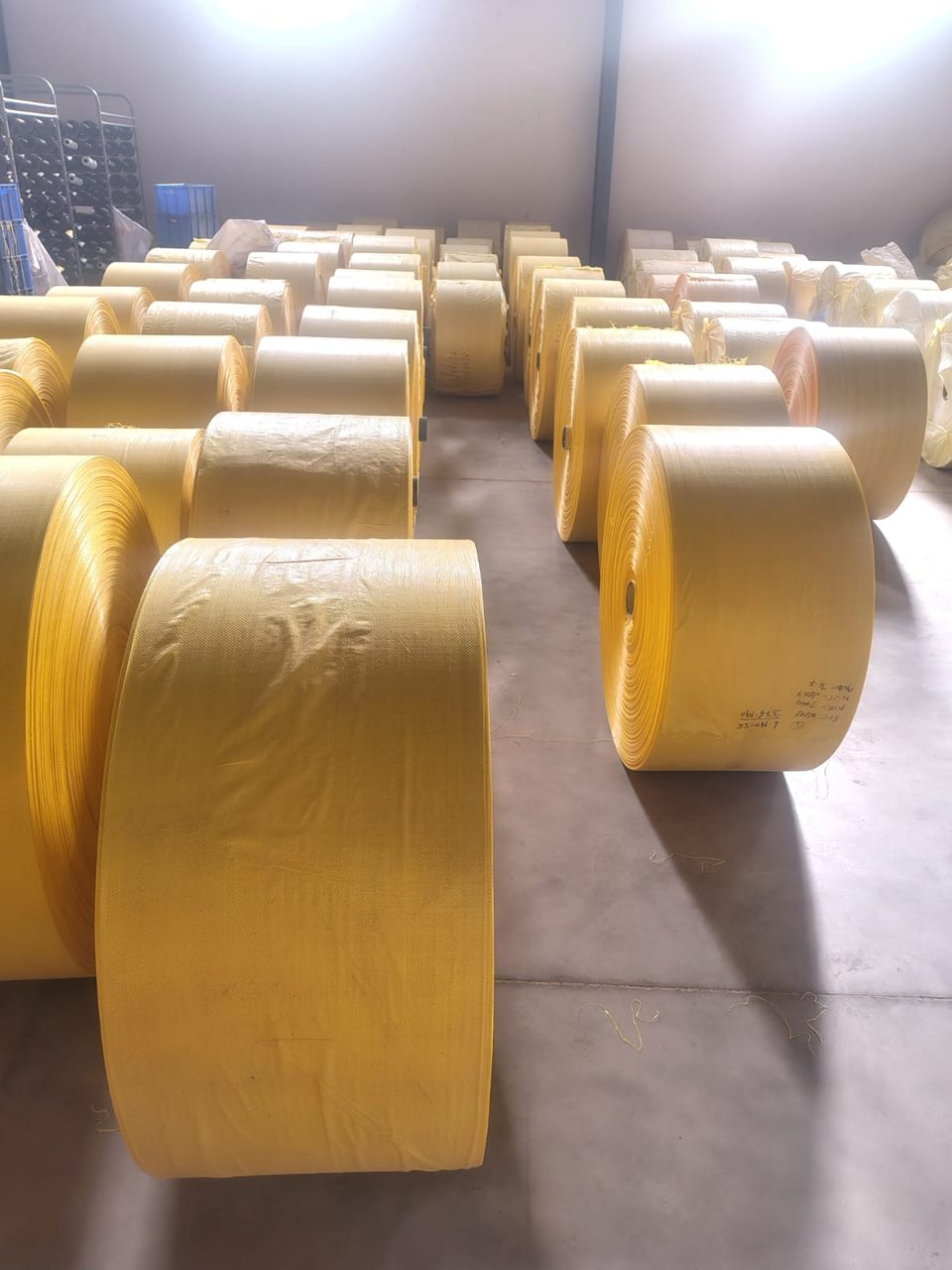 Rows of yellow woven fabric rolls in warehouse