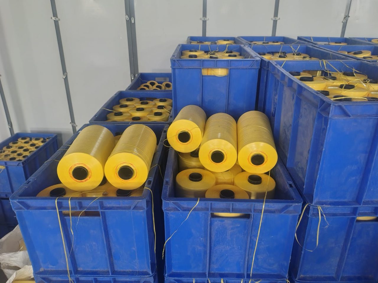 Crates of yellow PP tape yarn bobbins in storage