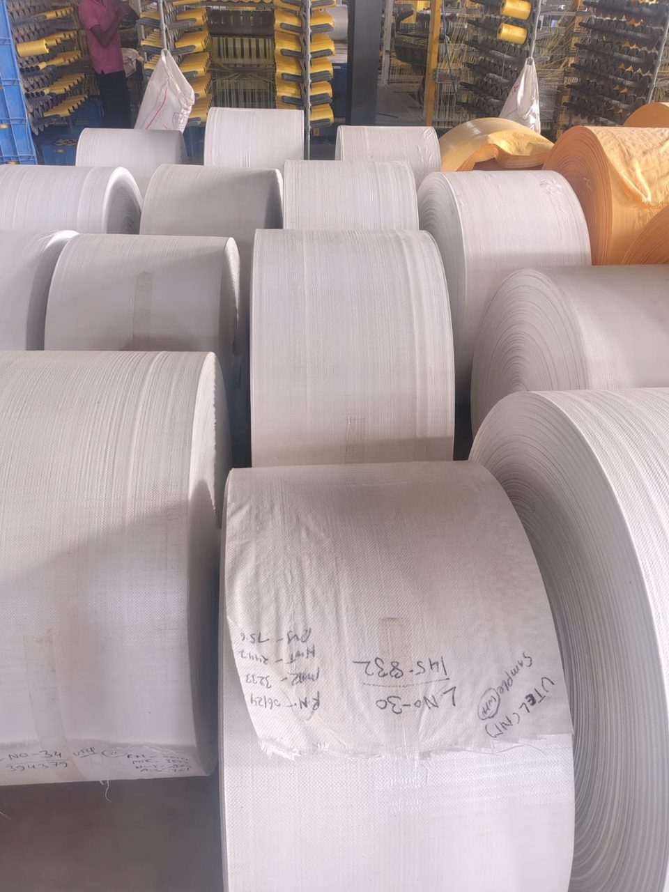 Stacks of white PP woven fabric rolls with job cards